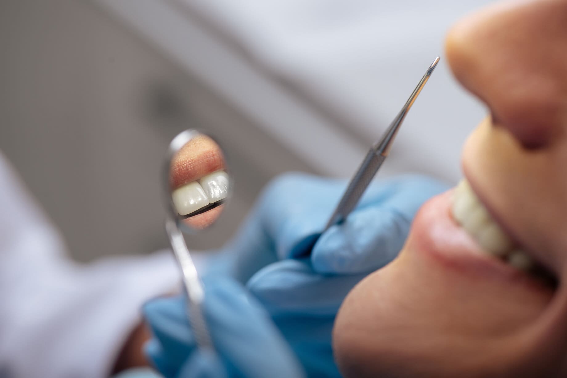 dentist in latex gloves holding dental instruments near smiling man