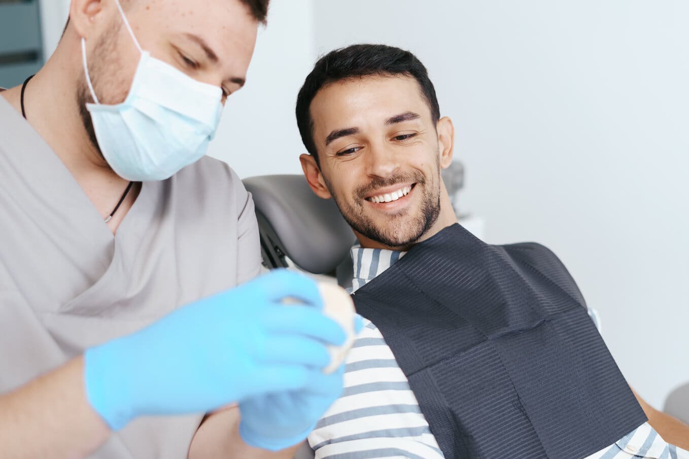 Male dentist showing patient the artificial dentures